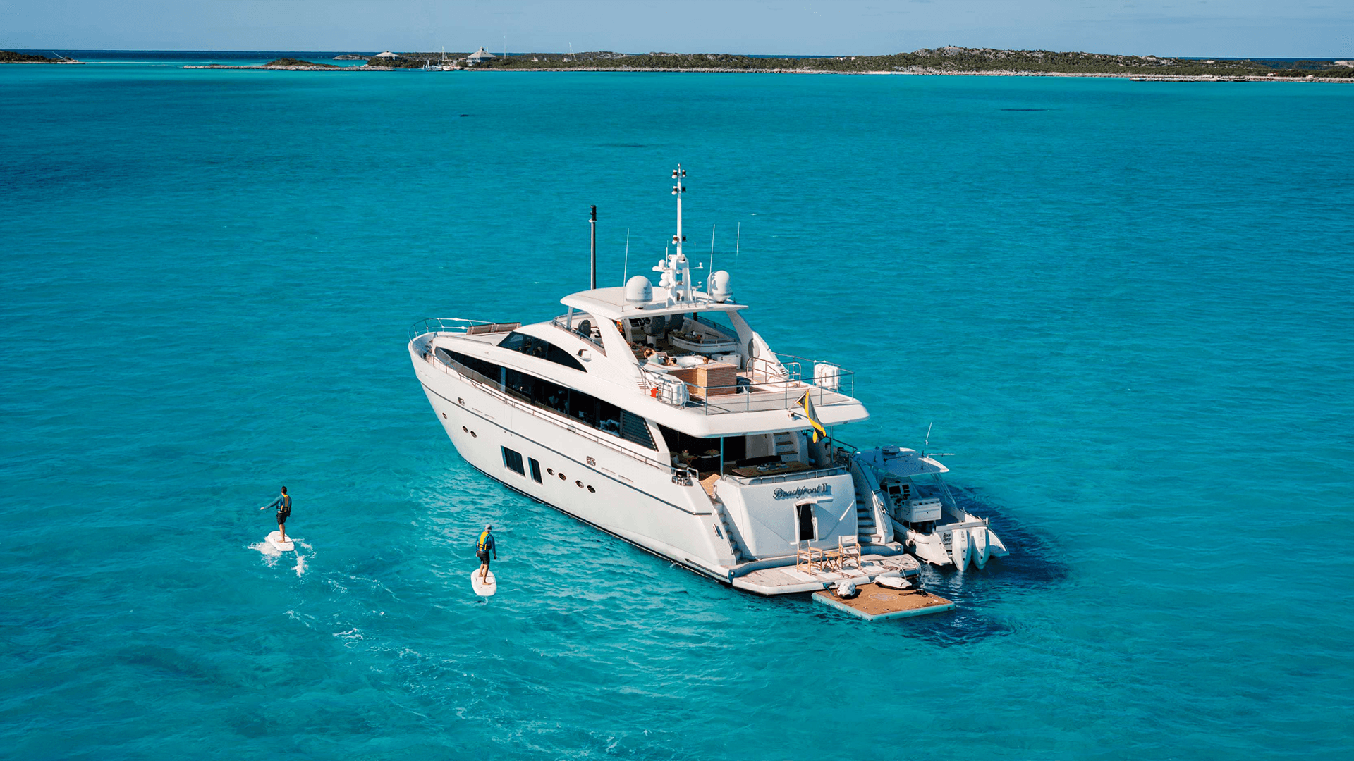 people paddle boarding around the beachfront II yacht motor boat